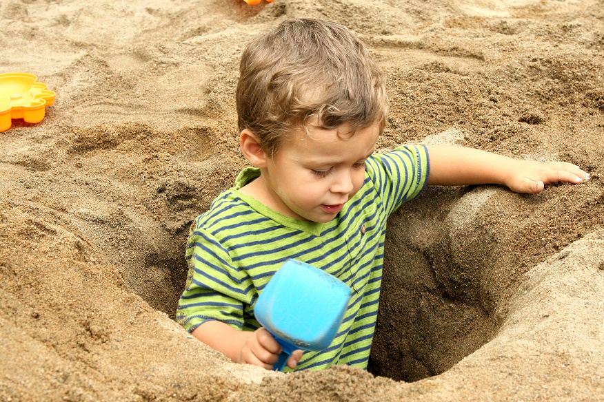 Niño busca tesoro en la playa