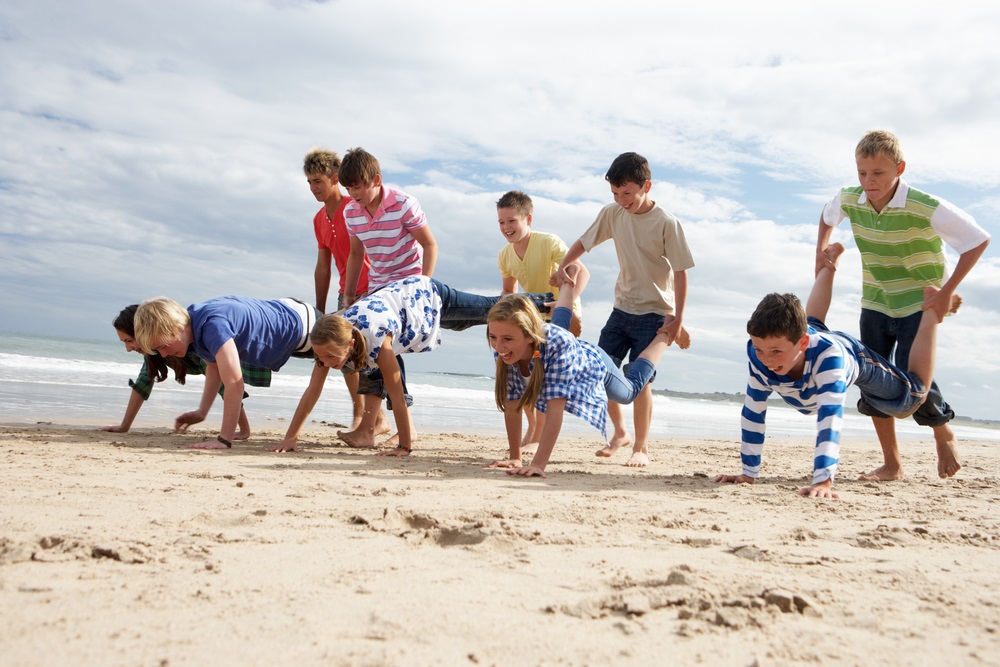 Niños jugando a carretillas en la playa